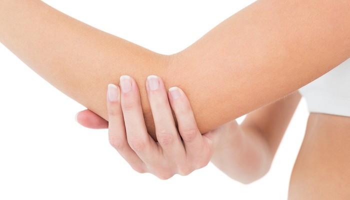 Close-up mid section of a young woman with elbow pain over white background