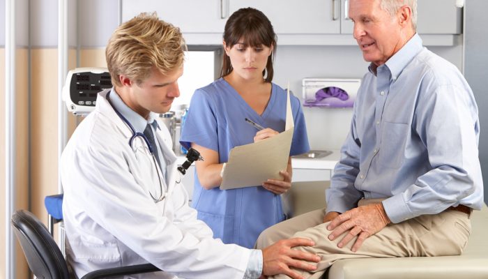 Doctor Examining Male Patient With Knee Pain