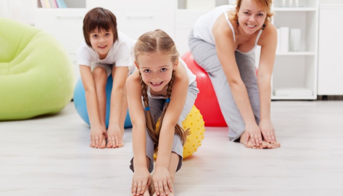 Happy healthy family - woman and kids - doing stretching exercises at home